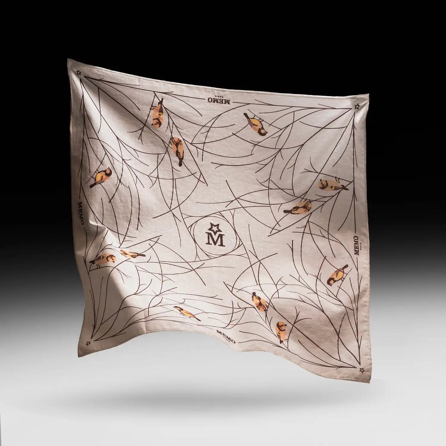A cream-colored square silk scarf with a pattern of black branches and small, colorful birds.