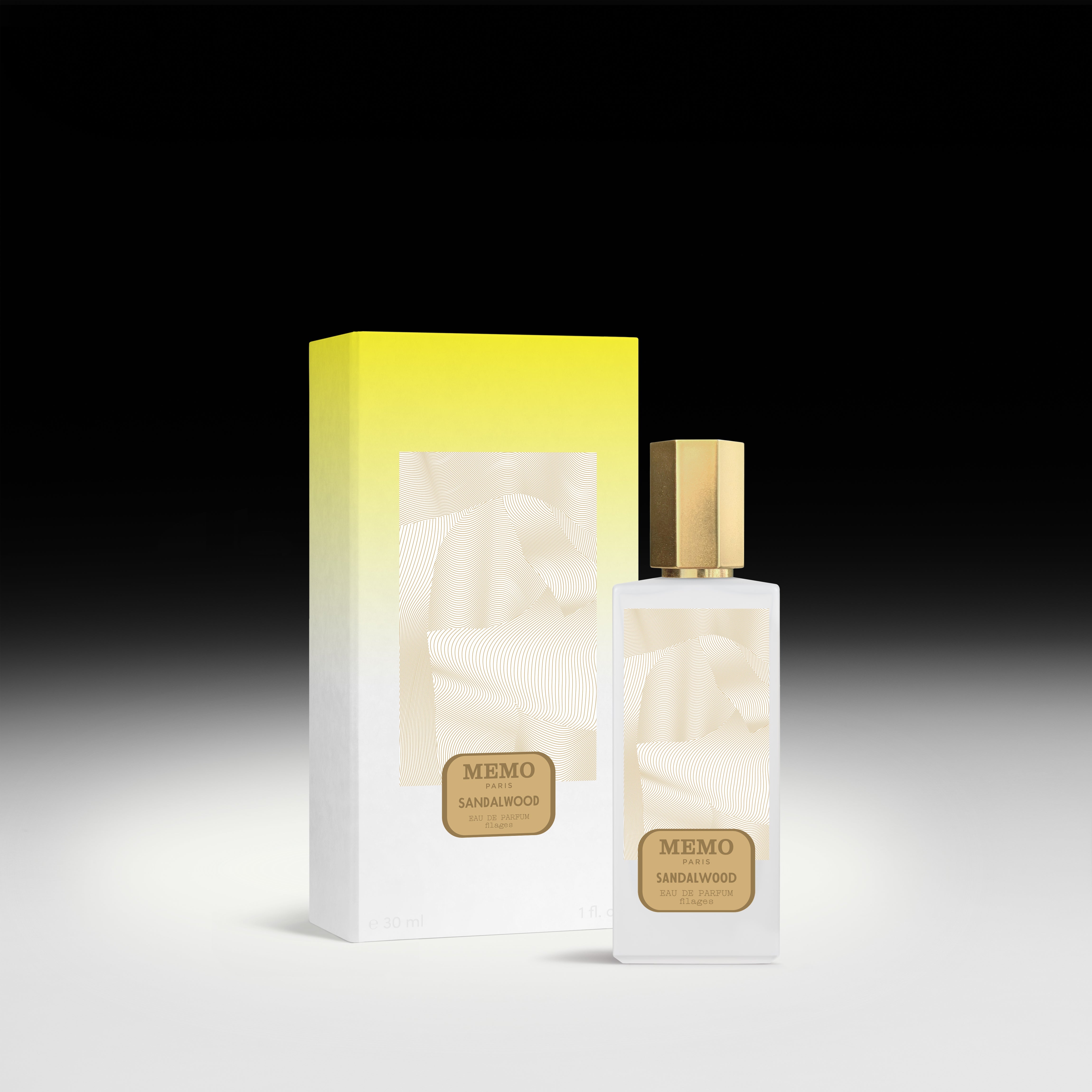 A sleek white glass bottle of memo paris essences filages sandalwood filages eau perfume with gold cap beside yellow gradient box