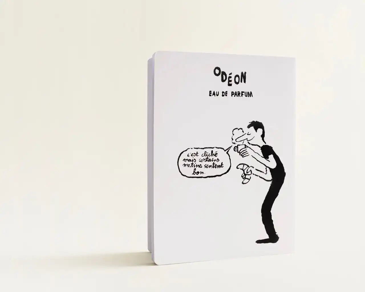 A white box with a black cartoon drawing of a person spraying perfume and a speech bubble.