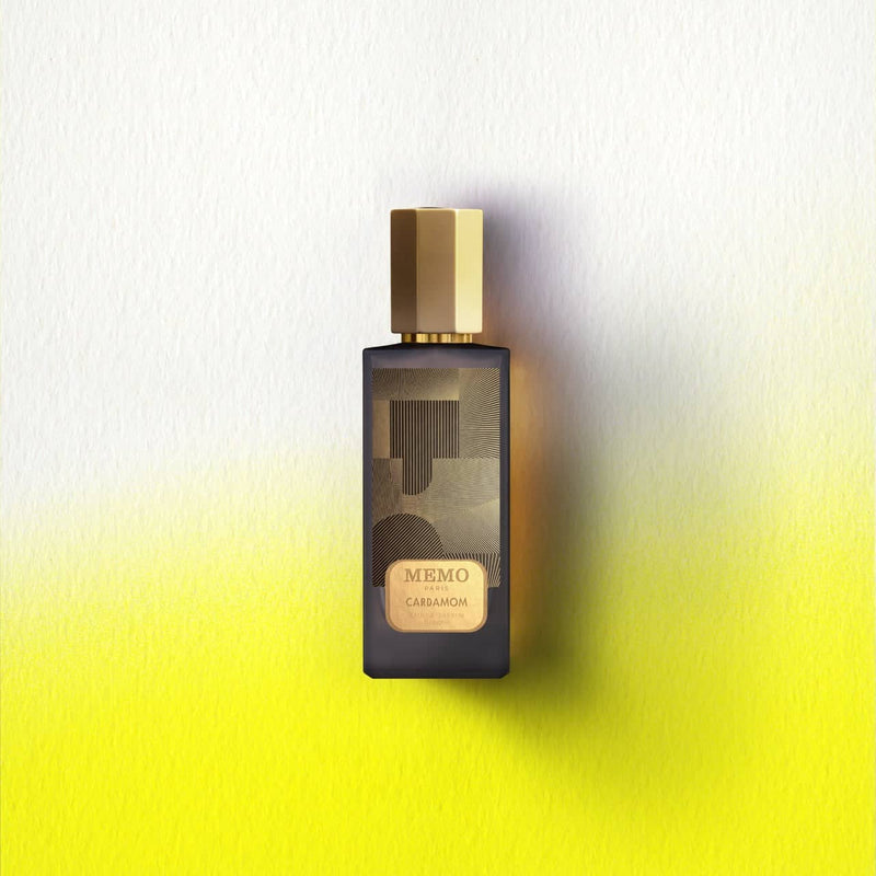 Dark glass perfume bottle with gold hexagonal cap and geometric patterned label, featuring ’memo paris carbamom’ branding.